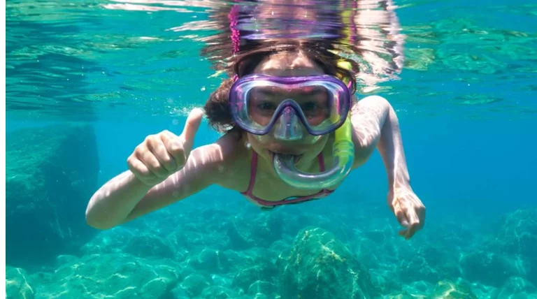 "Snorkeling companion swimming along coral reef"